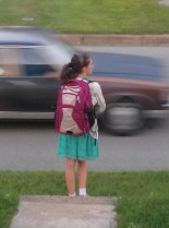 Teenager waiting with backpack as as car passes